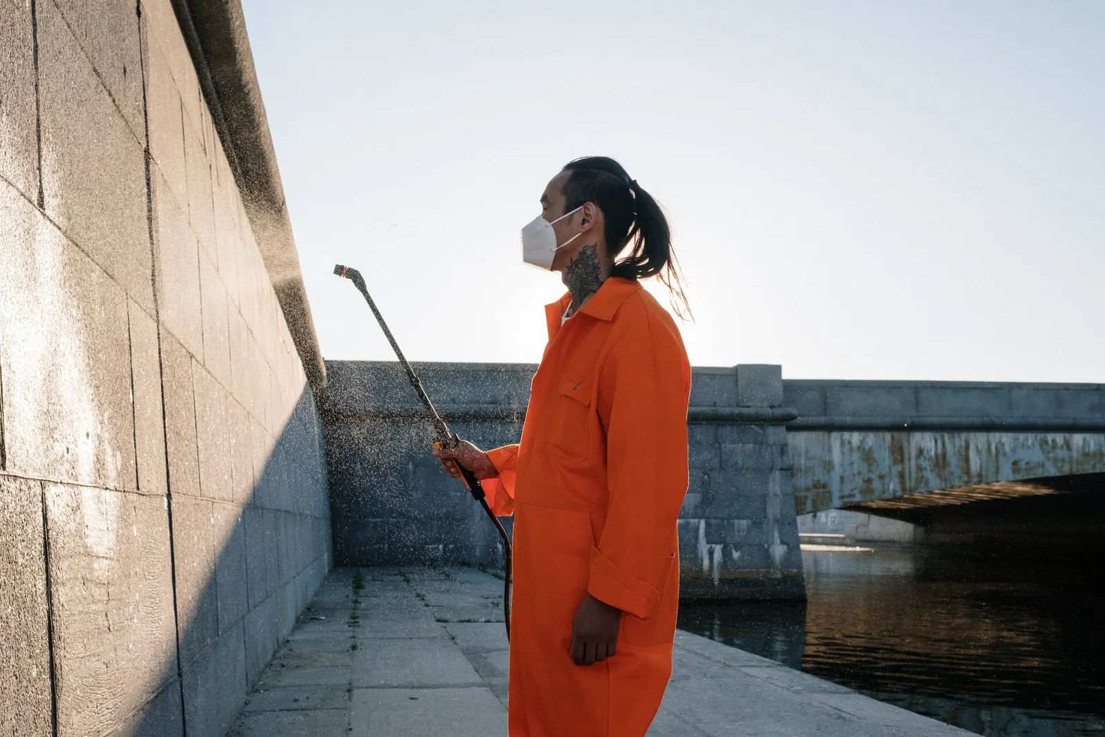 A pest control technician treating the exterior wall of a building